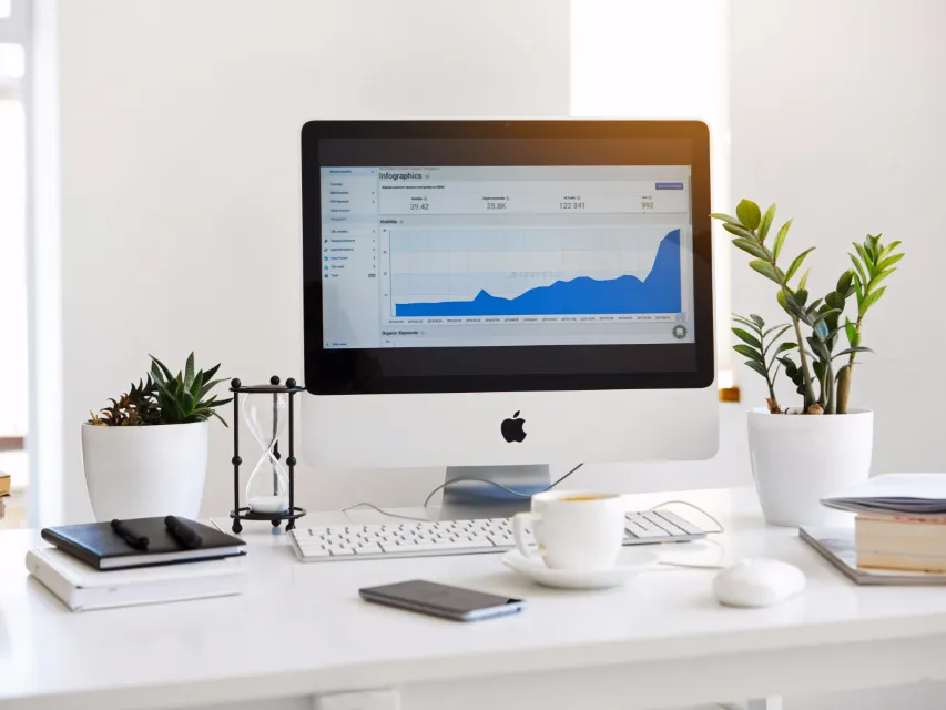 Desktop monitor showing a live analytics dashboard on a bright desk with plants